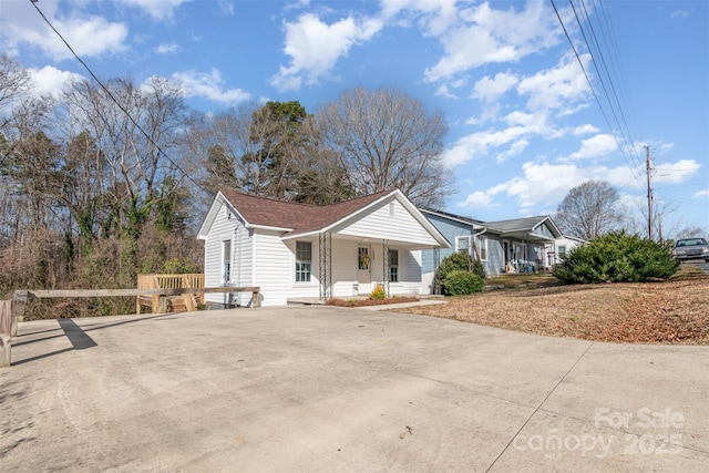 view of front of house with concrete driveway, a porch, and roof with shingles