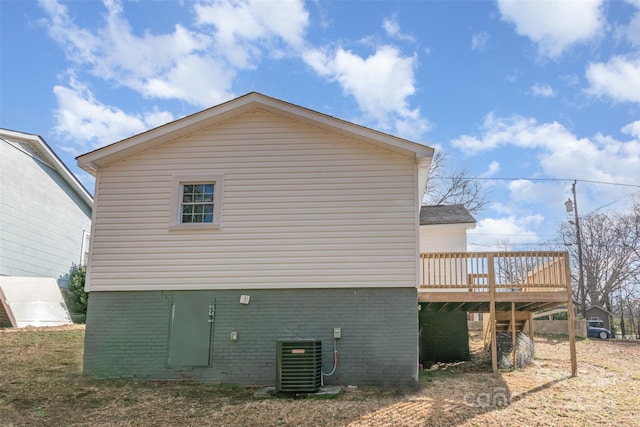 view of property exterior featuring a wooden deck, central AC, and brick siding