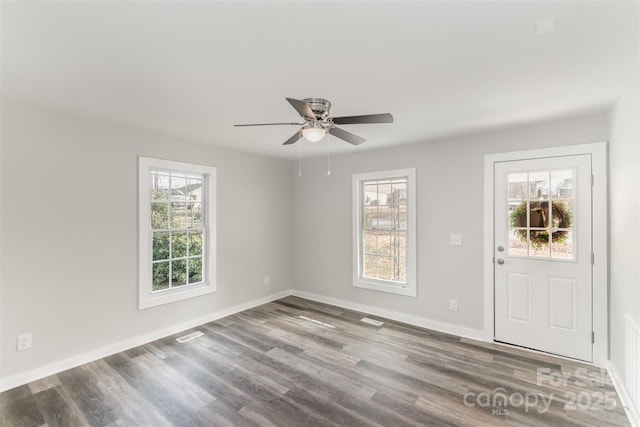 interior space featuring ceiling fan, visible vents, baseboards, and wood finished floors