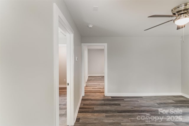 empty room featuring a ceiling fan, baseboards, and wood finished floors