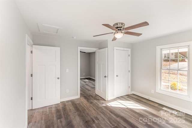 unfurnished bedroom featuring attic access, a ceiling fan, baseboards, and wood finished floors