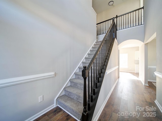 stairway featuring a high ceiling and wood-type flooring