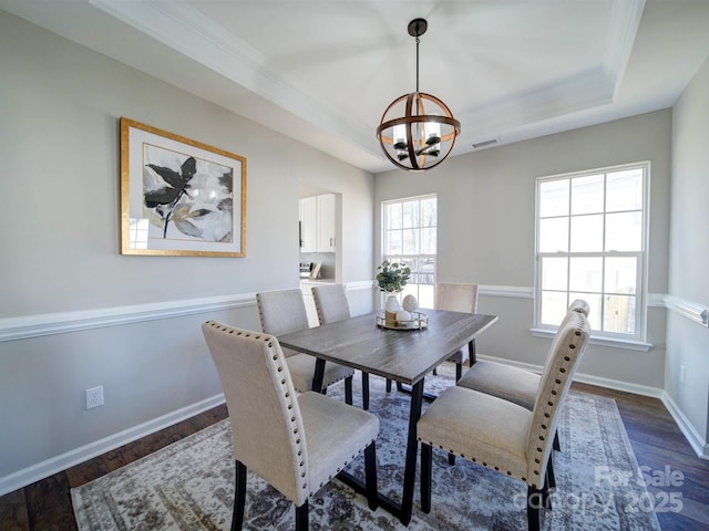 dining room with a tray ceiling, an inviting chandelier, dark wood-type flooring, and crown molding