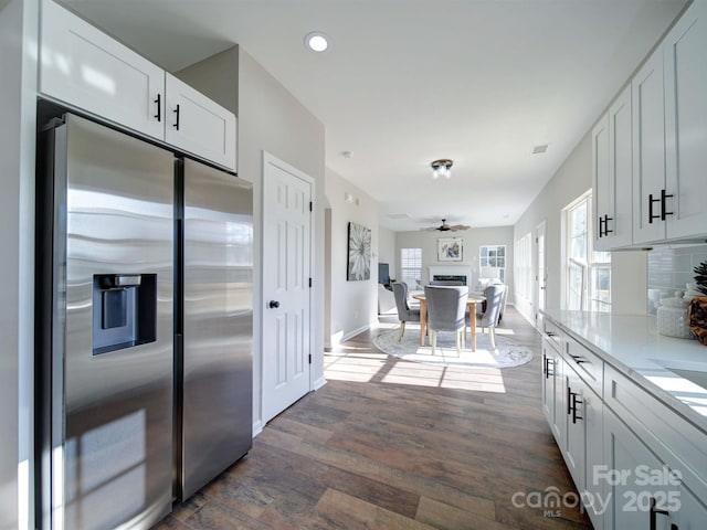 kitchen featuring white cabinetry, dark hardwood / wood-style floors, stainless steel fridge with ice dispenser, ceiling fan, and light stone countertops