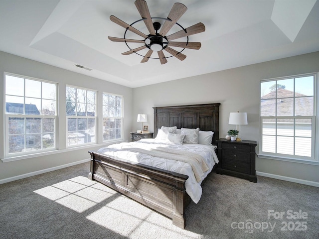 bedroom with a tray ceiling, ceiling fan, and carpet flooring