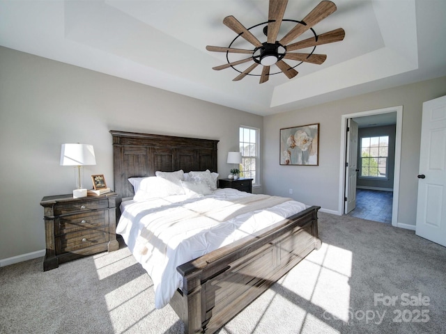 bedroom featuring a raised ceiling, light carpet, and ceiling fan