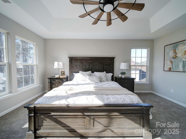 carpeted bedroom featuring ceiling fan and a tray ceiling