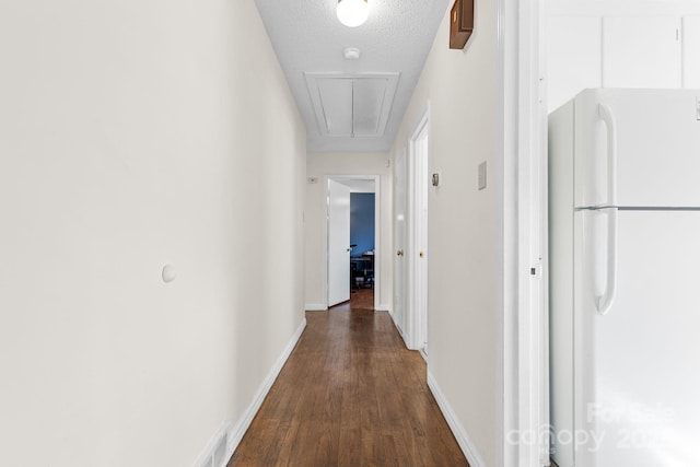 corridor with a textured ceiling and dark hardwood / wood-style flooring