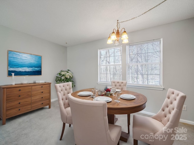 carpeted dining area featuring a notable chandelier, a textured ceiling, and baseboards