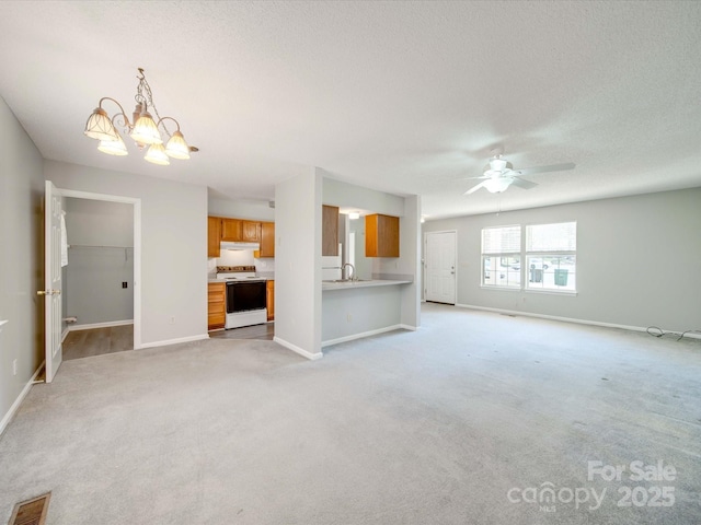 unfurnished living room with light colored carpet, visible vents, a textured ceiling, baseboards, and ceiling fan with notable chandelier