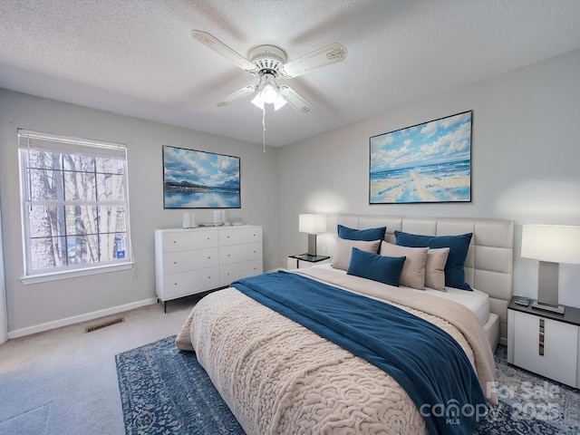 bedroom featuring a textured ceiling, carpet flooring, visible vents, and baseboards