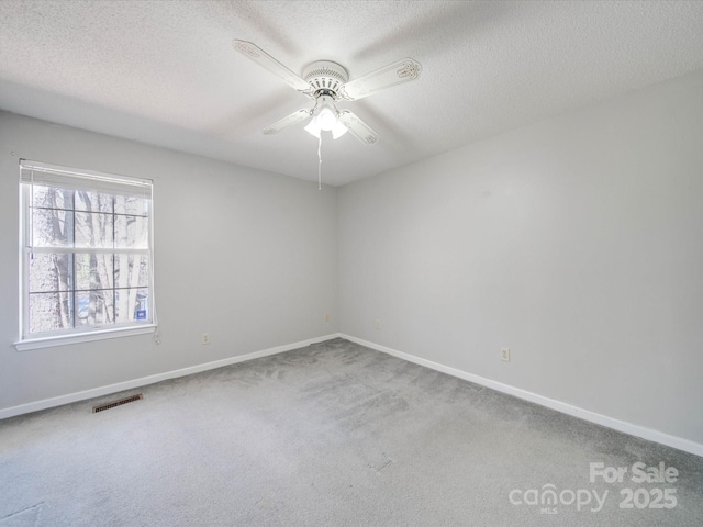 carpeted spare room featuring visible vents, a textured ceiling, and baseboards