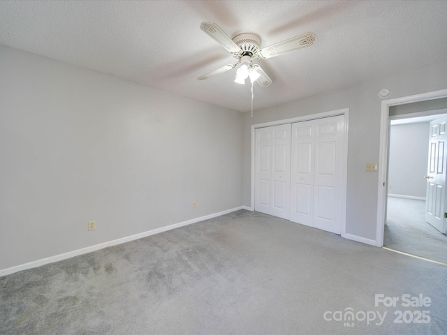 unfurnished bedroom featuring a textured ceiling, carpet floors, a ceiling fan, baseboards, and a closet