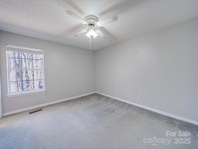 carpeted empty room featuring a textured ceiling, ceiling fan, visible vents, and baseboards