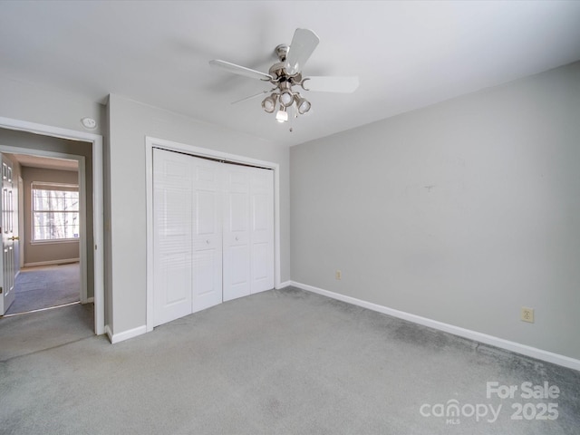 unfurnished bedroom featuring carpet floors, a closet, baseboards, and a ceiling fan