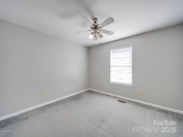 carpeted spare room with ceiling fan, visible vents, and baseboards