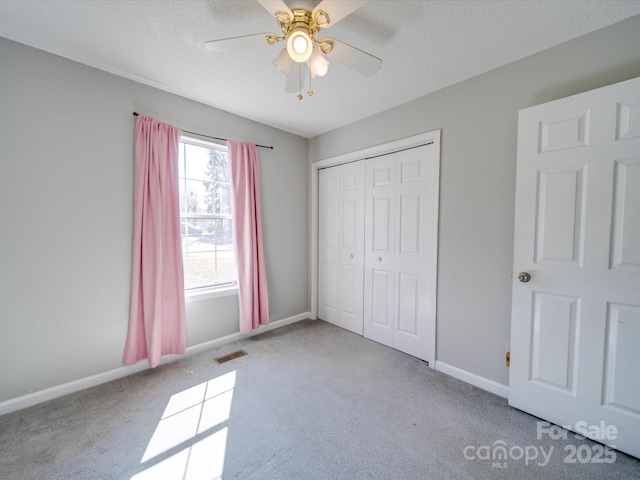 unfurnished bedroom with baseboards, a textured ceiling, visible vents, and carpet flooring