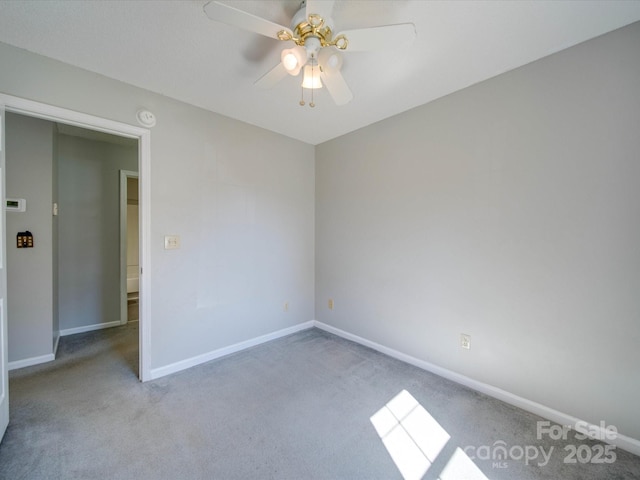 carpeted empty room with ceiling fan and baseboards