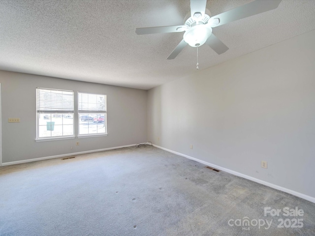 carpeted empty room featuring baseboards, visible vents, and a textured ceiling