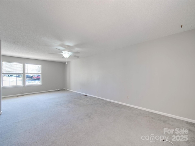 unfurnished room with a ceiling fan, carpet, a textured ceiling, and baseboards