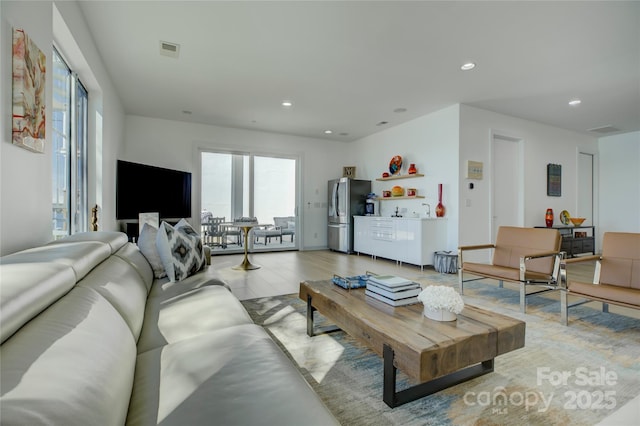 living room with light wood-type flooring, visible vents, and recessed lighting