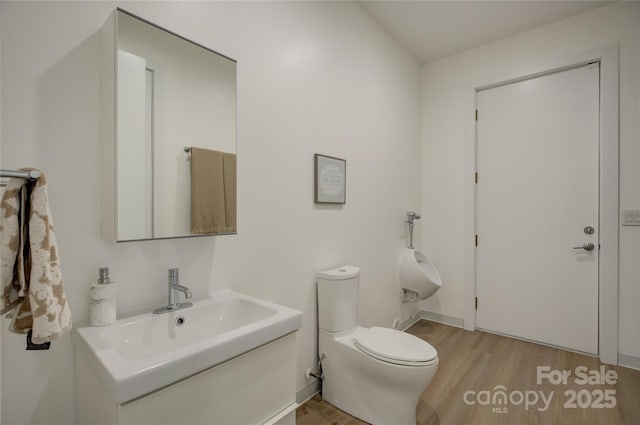 half bath with toilet, a sink, and wood finished floors