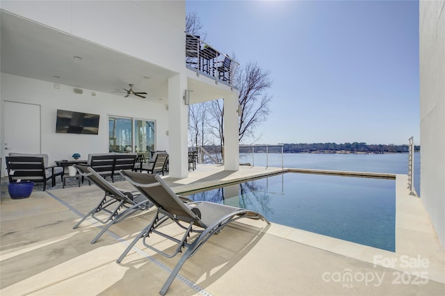 pool featuring a ceiling fan, a water view, and a patio