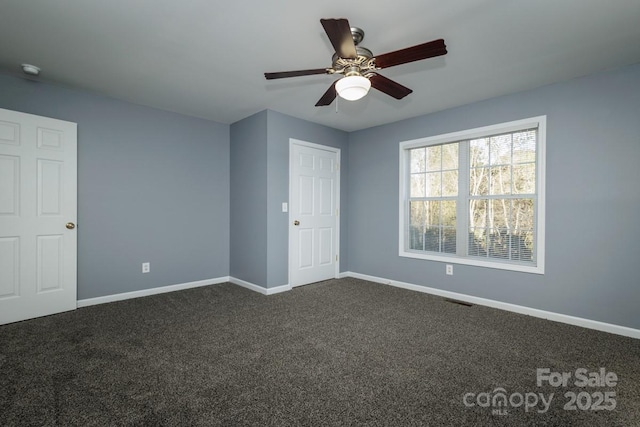 unfurnished bedroom with ceiling fan and dark colored carpet