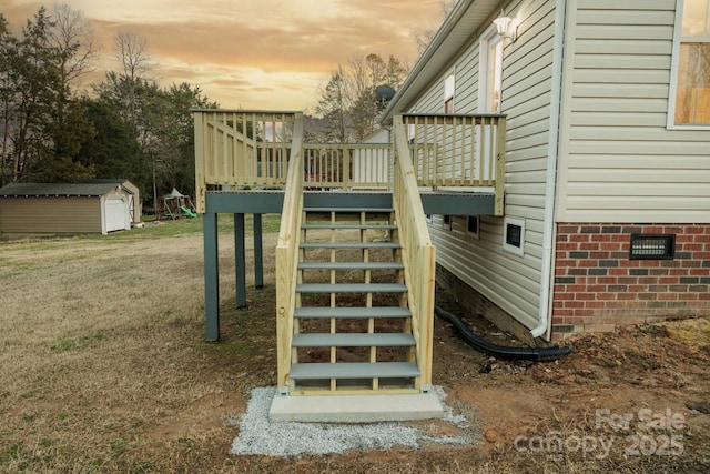 playground at dusk with a lawn, a deck, and a shed