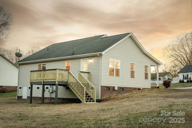 back house at dusk with a yard and a wooden deck