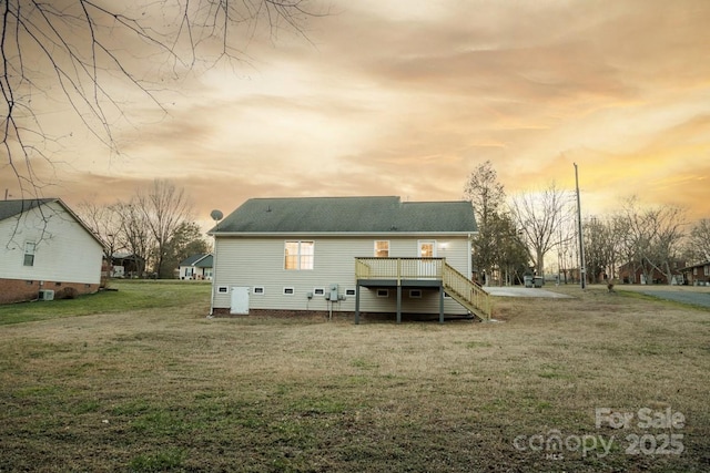 back house at dusk with a deck and a yard