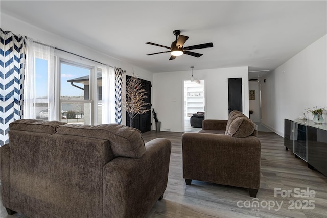 living room with ceiling fan, baseboards, and wood finished floors