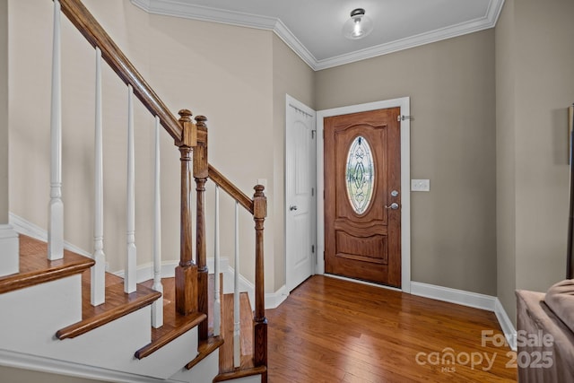 foyer entrance with stairs, baseboards, wood finished floors, and crown molding