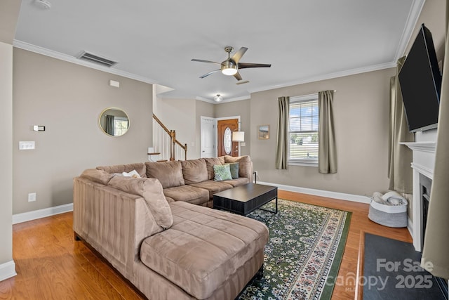 living room featuring visible vents, stairway, a fireplace with flush hearth, and wood finished floors