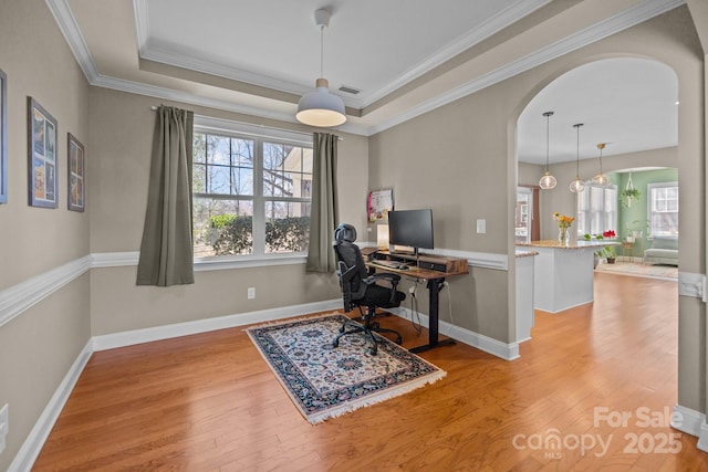 office area with visible vents, arched walkways, a raised ceiling, and wood finished floors