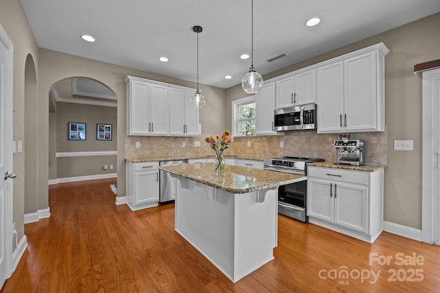 kitchen with arched walkways, visible vents, white cabinets, and stainless steel appliances