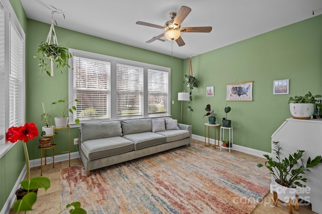 living area featuring baseboards and ceiling fan