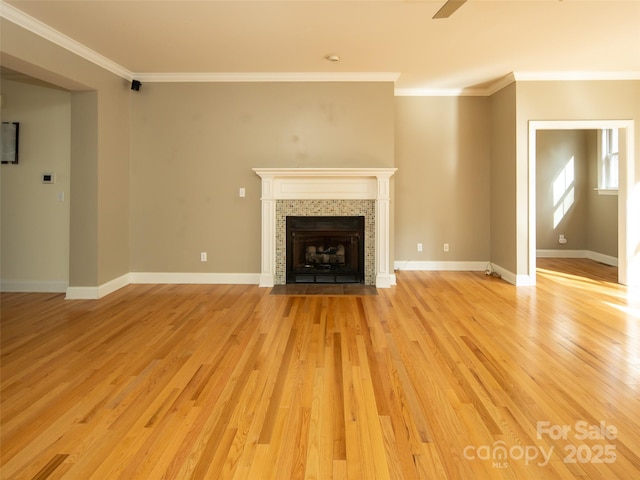 unfurnished living room featuring ornamental molding, a tile fireplace, and light hardwood / wood-style flooring