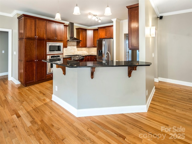 kitchen featuring wall chimney range hood, light hardwood / wood-style floors, stainless steel appliances, a breakfast bar area, and ornamental molding