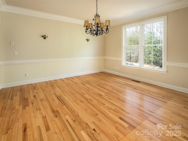 empty room with crown molding, an inviting chandelier, and light hardwood / wood-style flooring