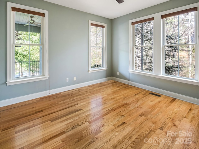 spare room featuring ceiling fan, light wood-type flooring, and plenty of natural light