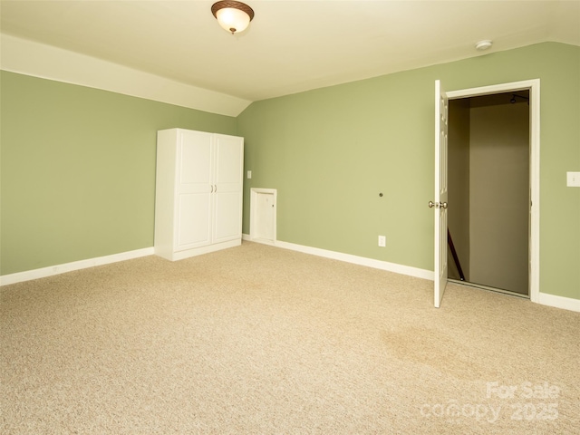 unfurnished bedroom featuring light carpet and vaulted ceiling