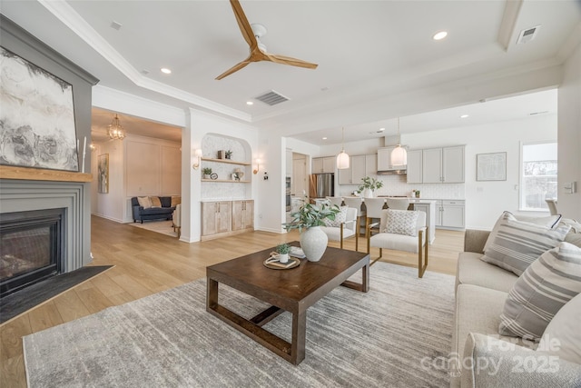 living room with visible vents, crown molding, and light wood-style flooring