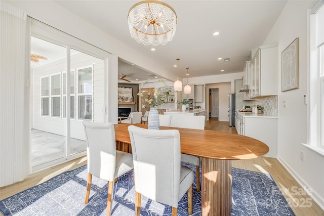 dining space with a notable chandelier, recessed lighting, light wood-type flooring, and a healthy amount of sunlight