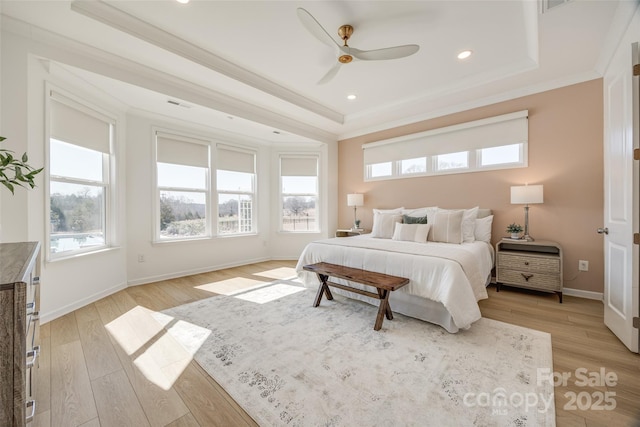 bedroom with a tray ceiling, visible vents, light wood-style flooring, ornamental molding, and baseboards