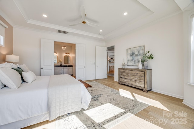 bedroom featuring light wood finished floors, crown molding, visible vents, and a tray ceiling