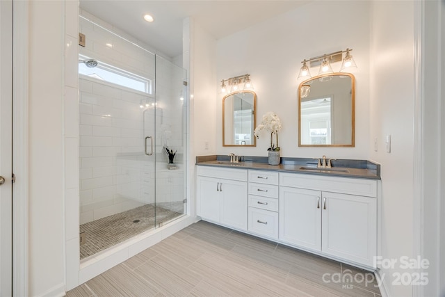 bathroom featuring double vanity, a shower stall, a sink, and recessed lighting