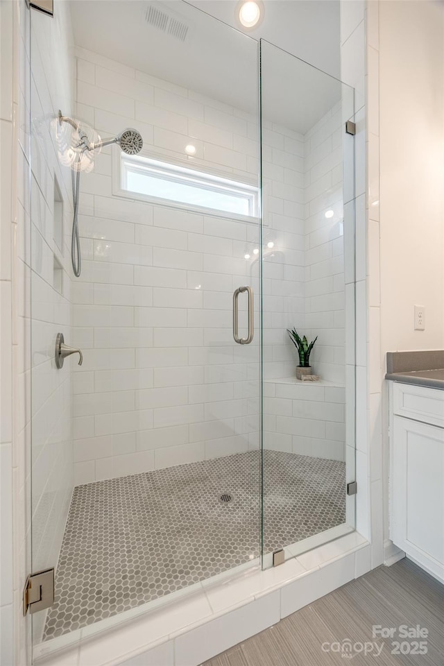 bathroom with a stall shower, visible vents, and vanity