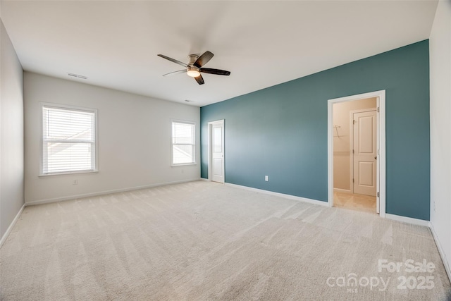 unfurnished room with carpet floors, a ceiling fan, visible vents, and baseboards