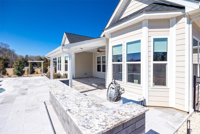 view of patio with ceiling fan and fence